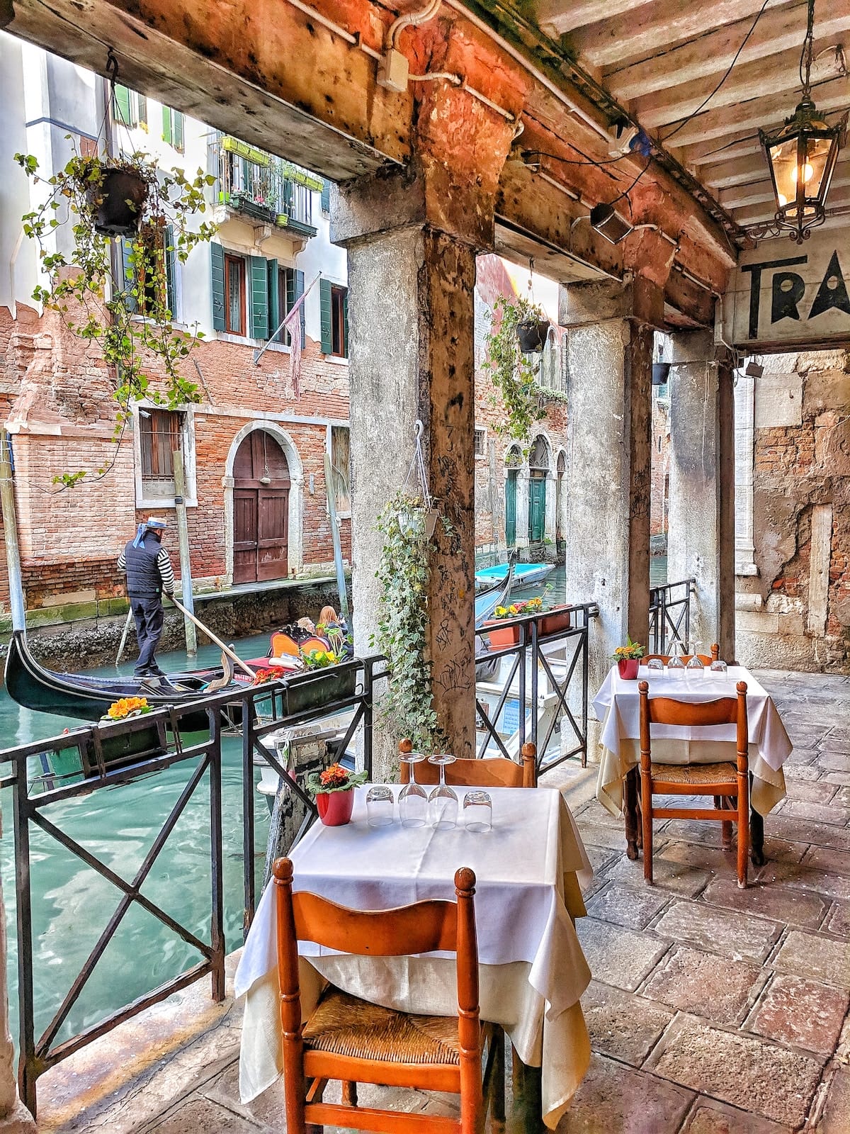 restaurant terrace in venice canals with gondola and gondolier day