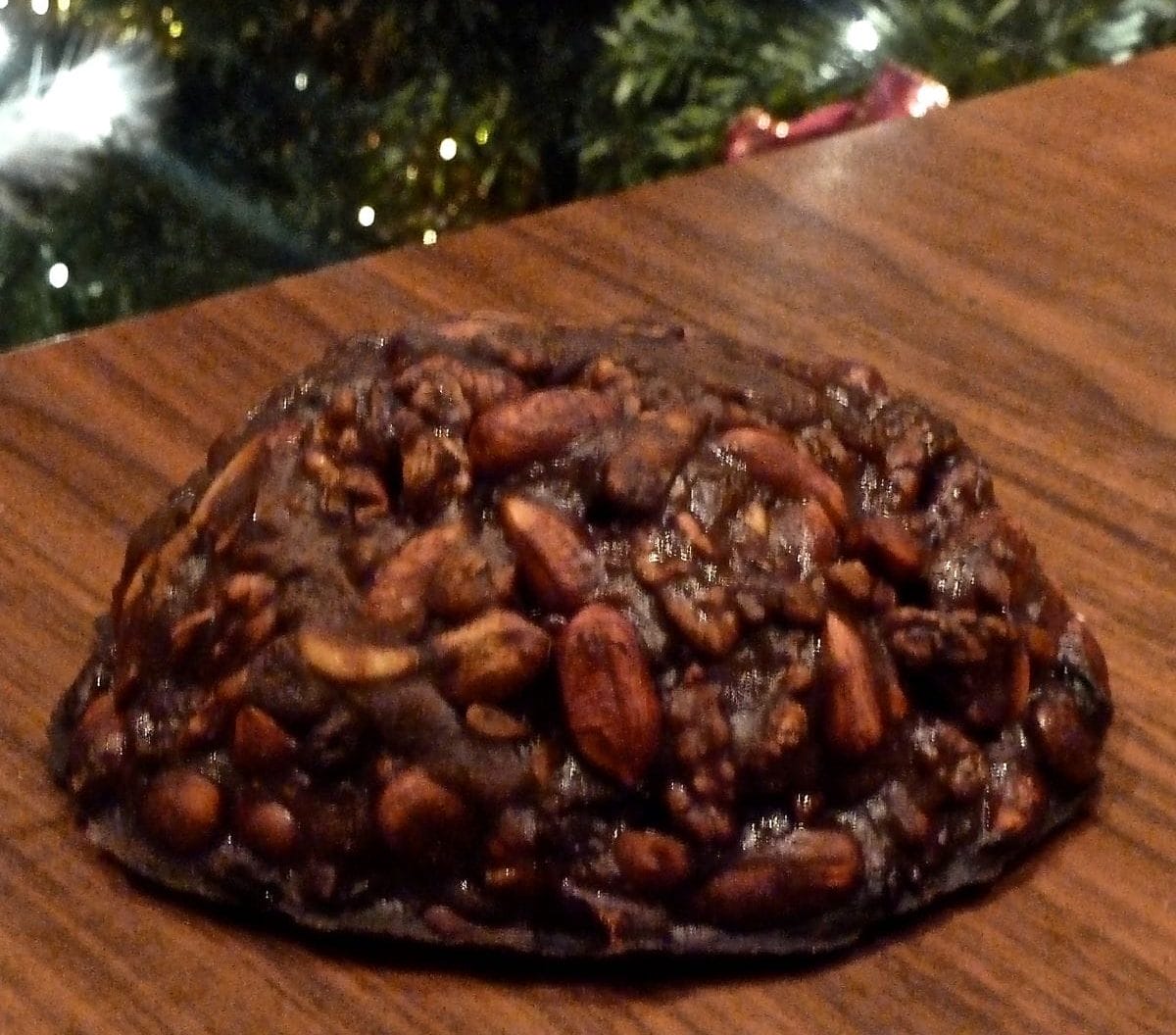 Italian Christmas treat, panpepato, in front of a Christmas tree. 