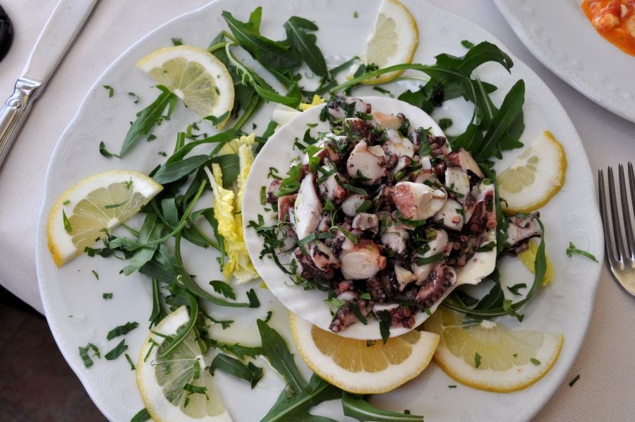 a plate of fresh seafood garnished with herbs and lemon, best eaten locally on the amalfi coast, 