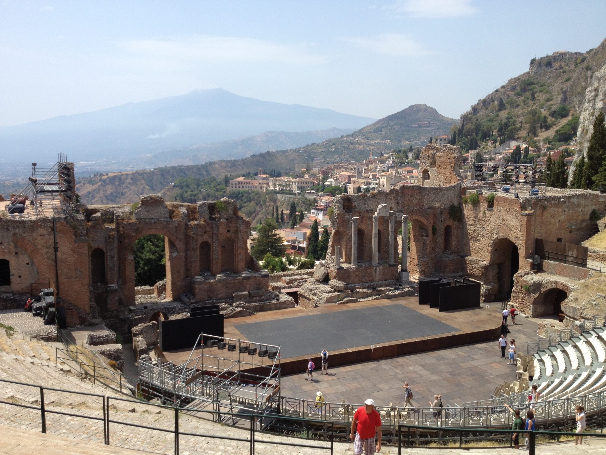 The Greek Theater in Taormina, top on the list of what to see in Taormina. These ruins show an ampitheater with columns and arches, with stunning views of Mount Etna in the background.