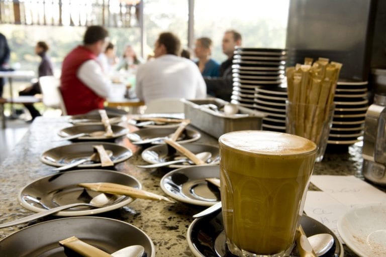 Coffee at cafe with people in the background. Find out how to drink coffee like an Italian!
