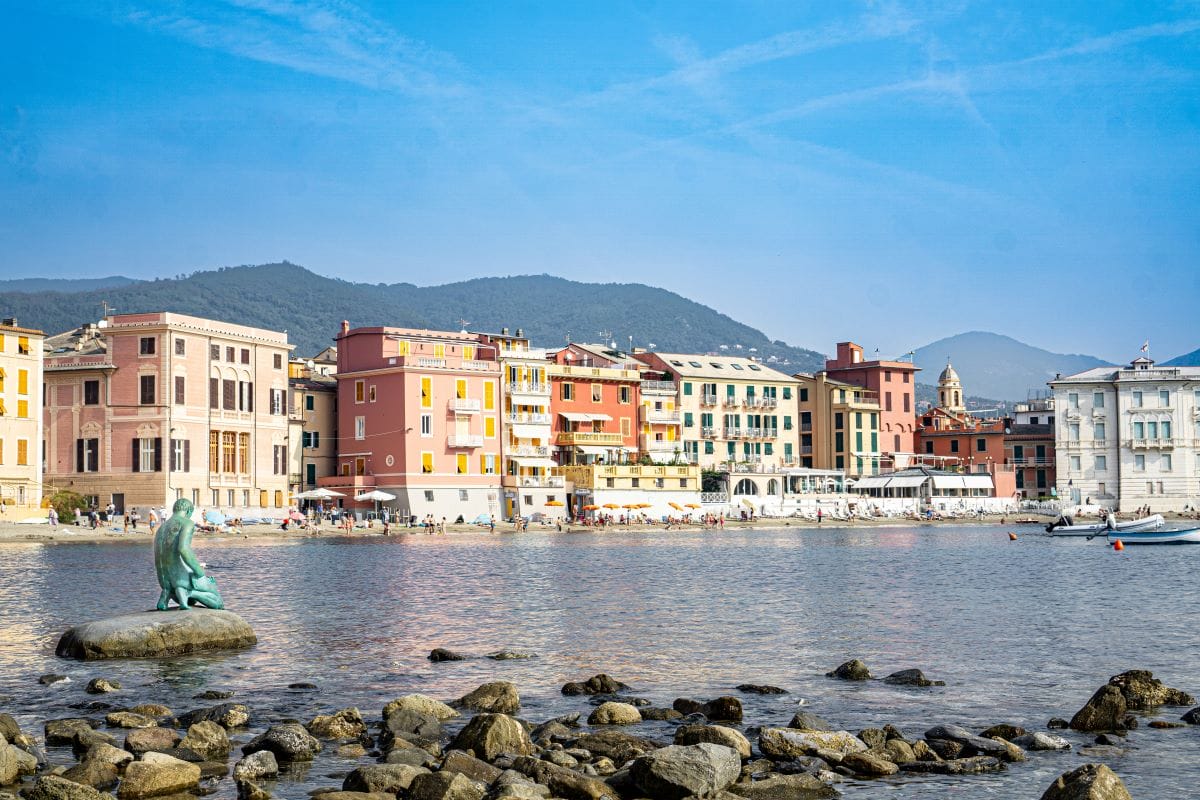 Panoramic view of an Italian Riviera town and statue in ocean. 