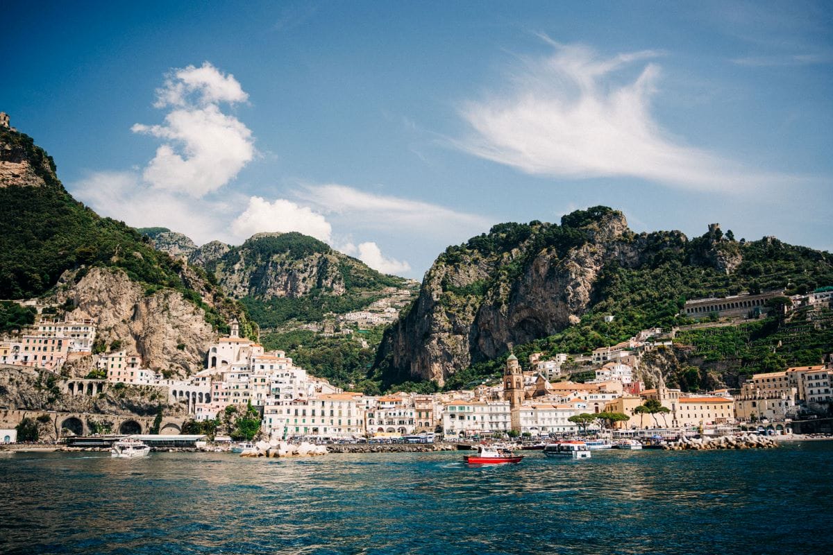 Coastal village along the Amalfi Coast in winter with colorful houses and mountains rising in the background.