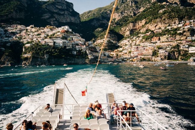 the wake of a boat as it leaves the coastline of a small town on the amalfi coast 