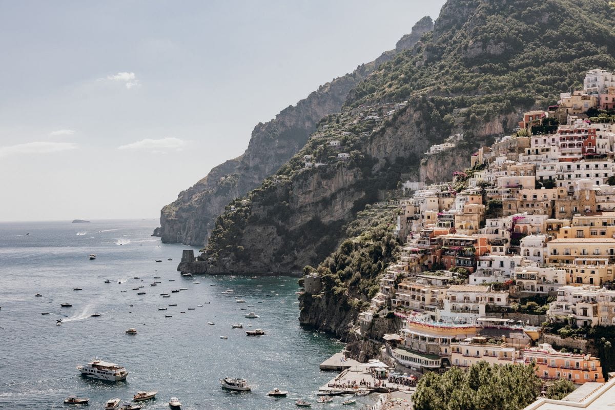 Colorful houses along the Amalfi Coast built into seaside cliffs with boats in the water.