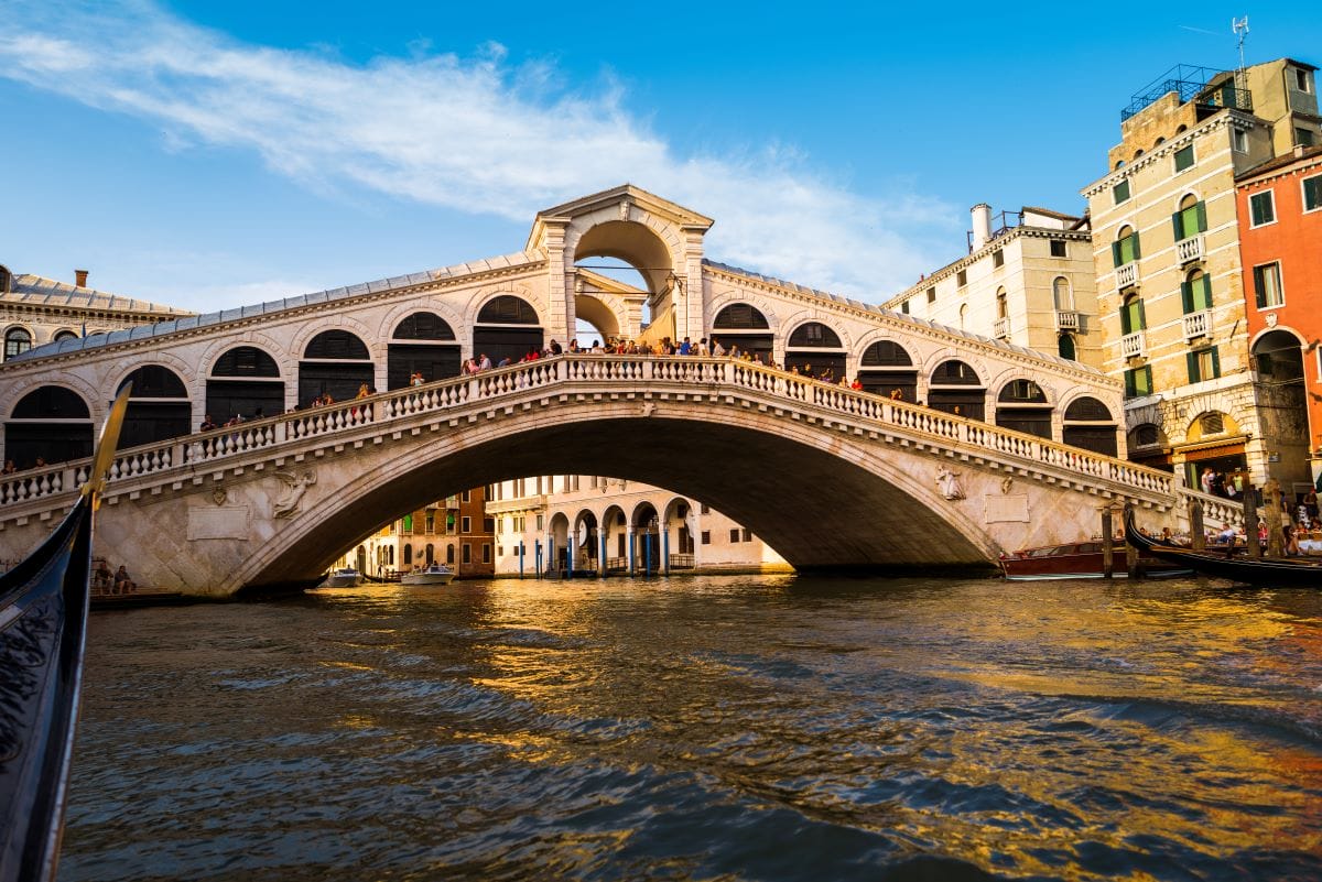 The sun shining on the famous Rialto Bridge in Venice. Take a gondola ride in venice to sail beneath it for a different view