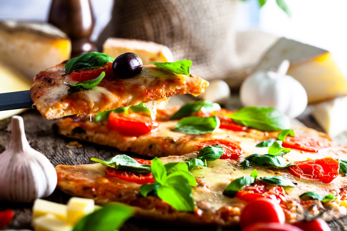 A colourful Napoli pizza with olives, fresh basil and ripe tomatoes