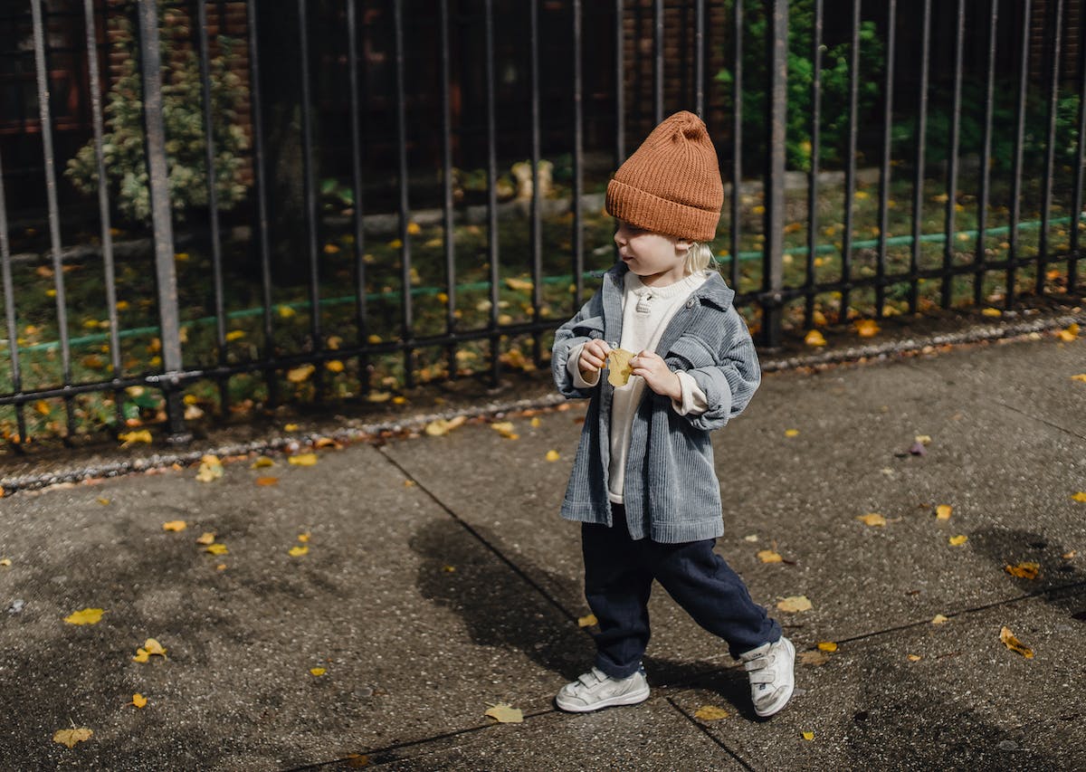 little boy wearing a beanie and walking
