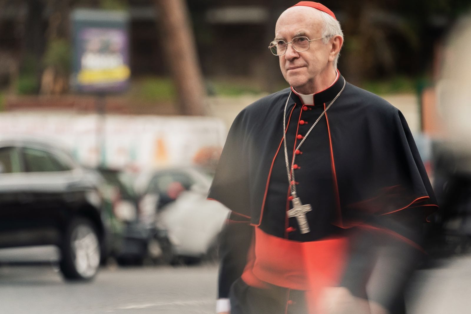 A still from the film The Two Popes, with  Jonathan Pryce playing Pope Francis wearing black and red robes