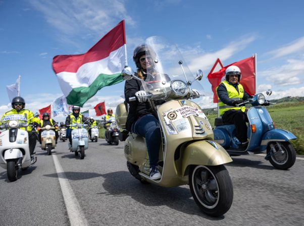 a parade of vespas riding with the italian falg to celebrate Vespa´s 80th birthday