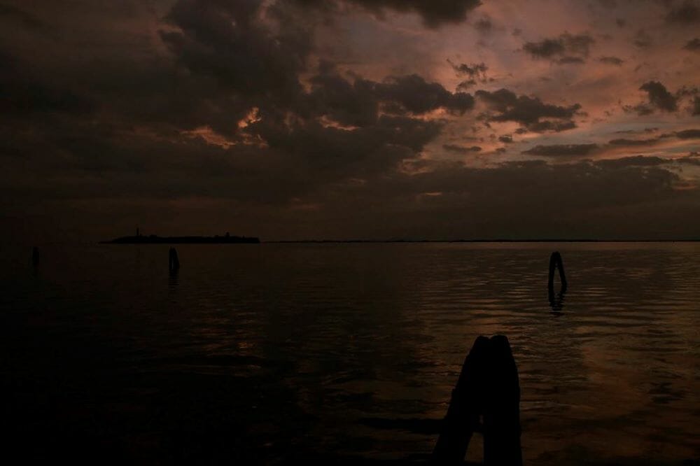 A view of Poveglia Island at night time, with storm clouds in the distance
