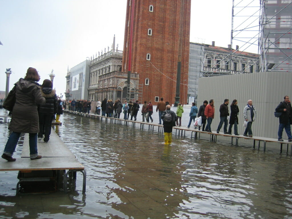 Visitors moving around elevated pedestrian walkways during Venice's Acqua Alta