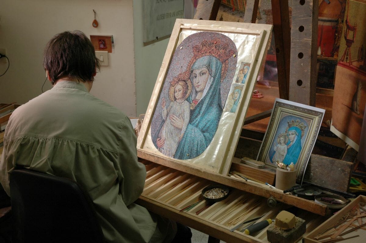 An artist in front of work at the Vatican Mosaic Studio