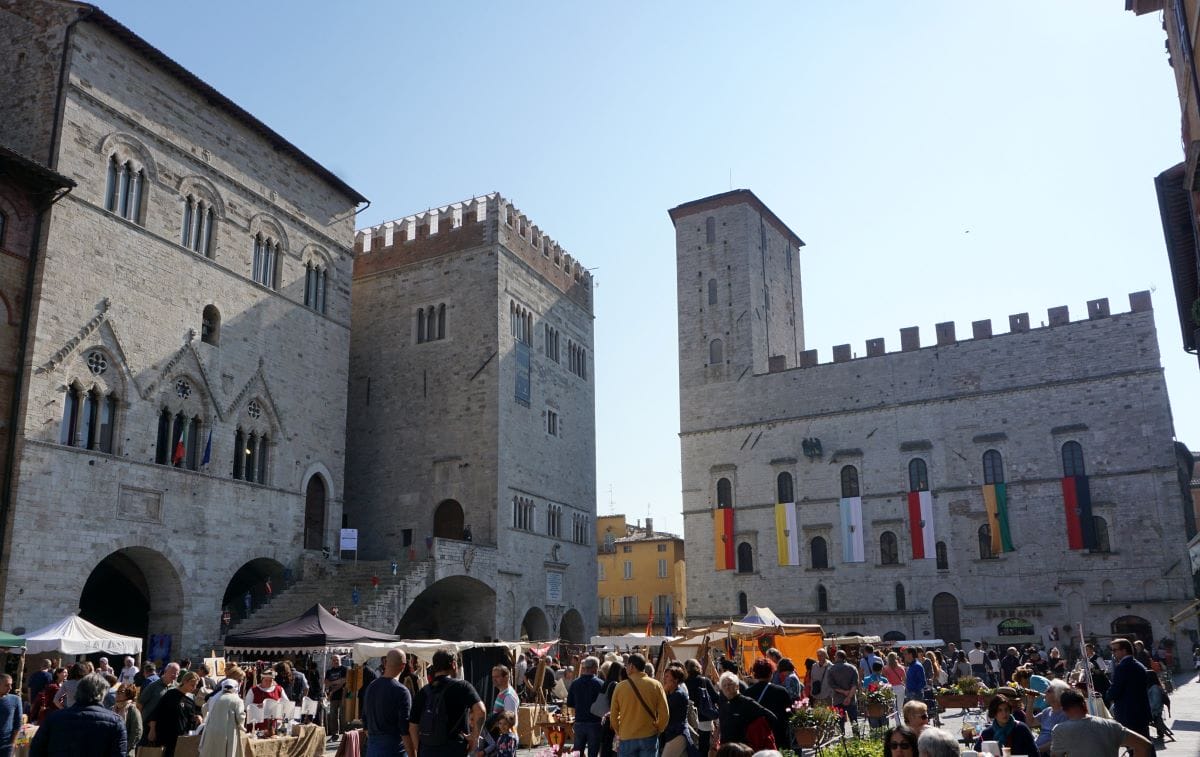 square with people shopping and historic buildings in the background