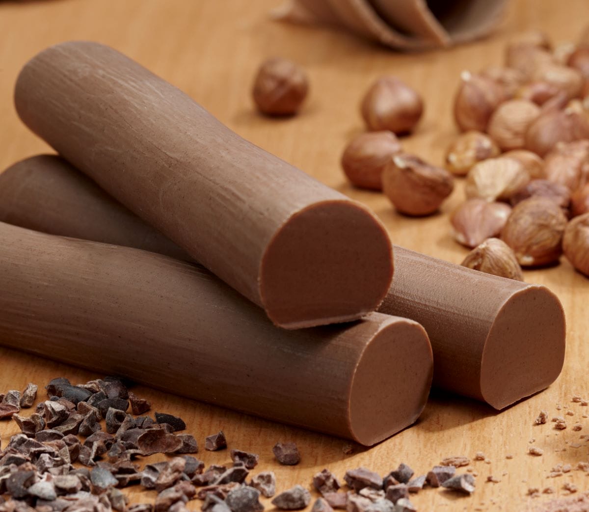 three round long bars of chocolate with hazelnuts in the background