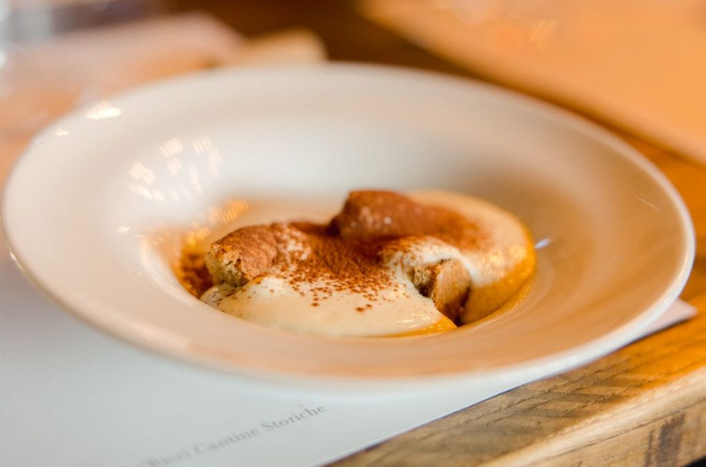A plate of freshly made tiramisu in a white ceramic bowl.
