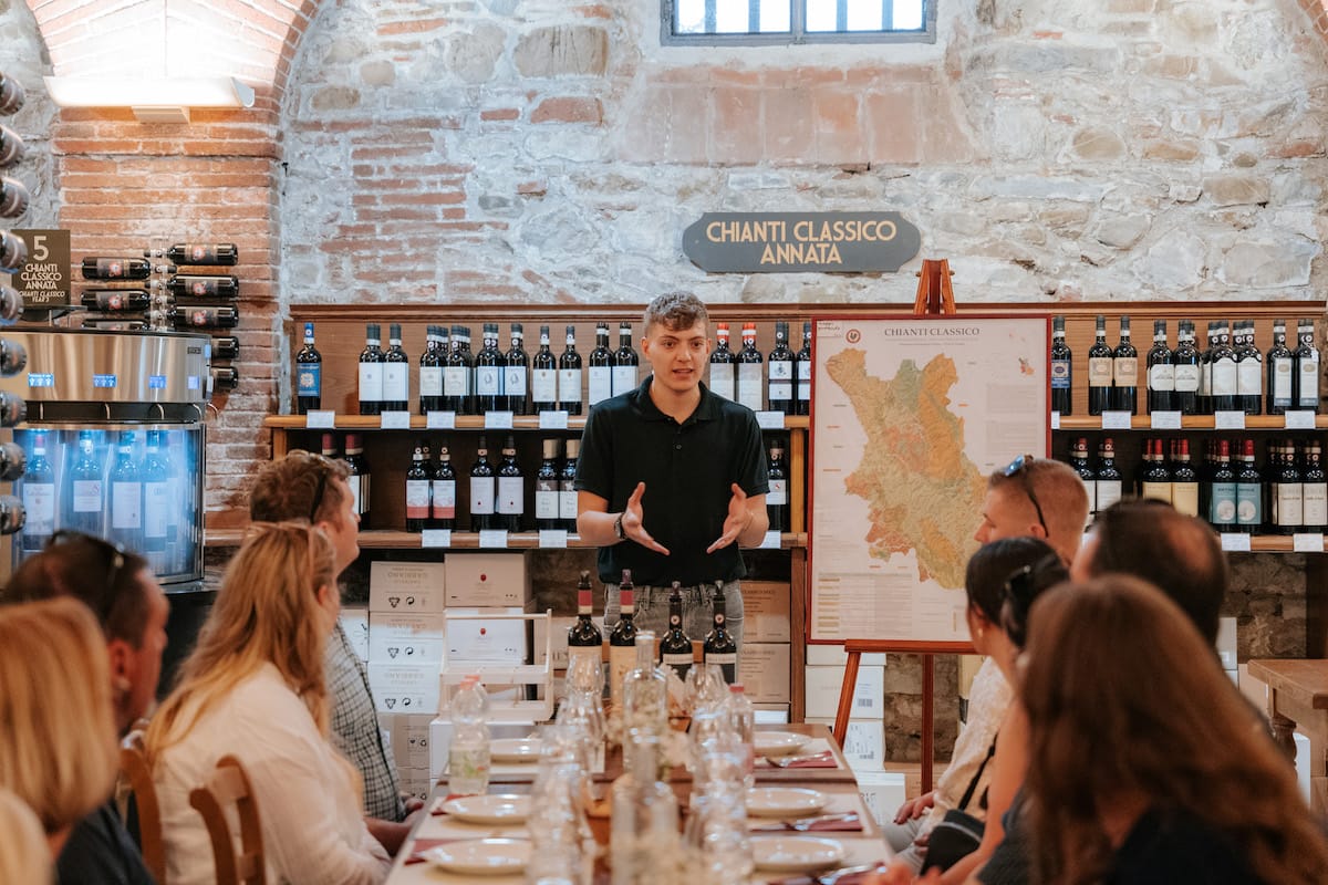 A person standing at the head of a table explaining a map of Chianti classico annata.