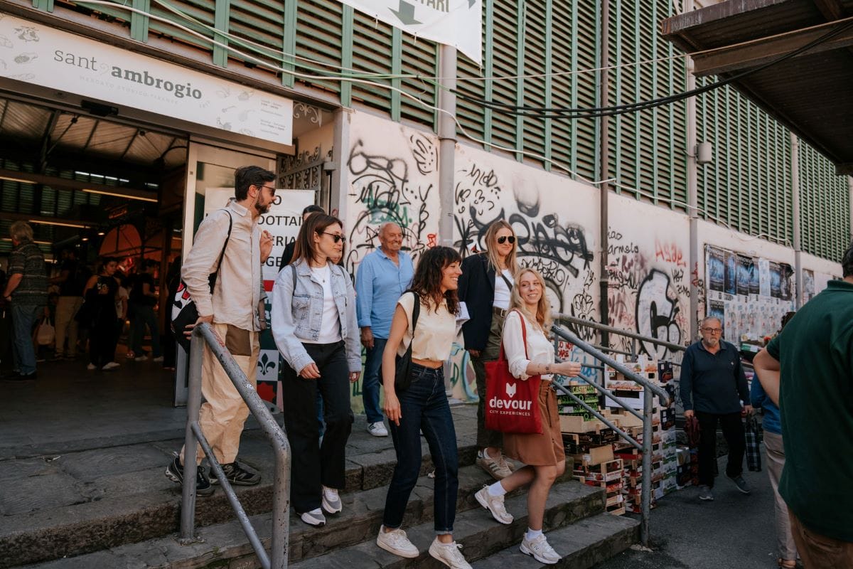 A group of people walking down the steps from a food market in Florence.