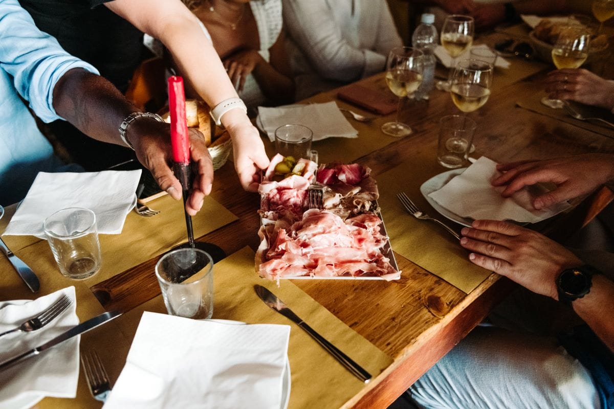 People sitting around a table enjoying a plate of charcuterie and wine.