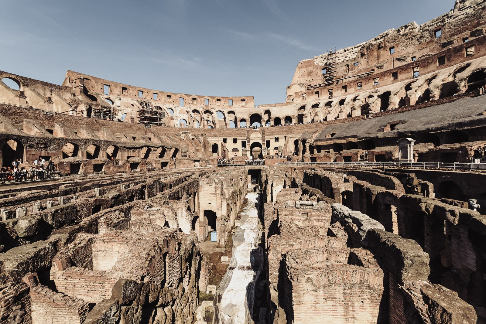 Interior view of the Colosseum with ruins, visible passageways, and an open arena floor.