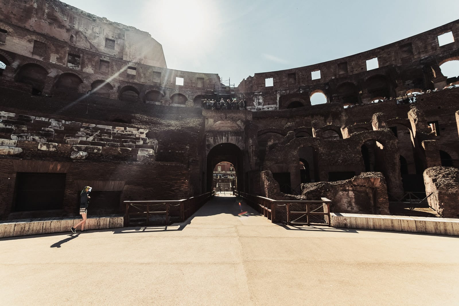 View of the Colosseum’s outer archways and open interior. A person walks through the passage