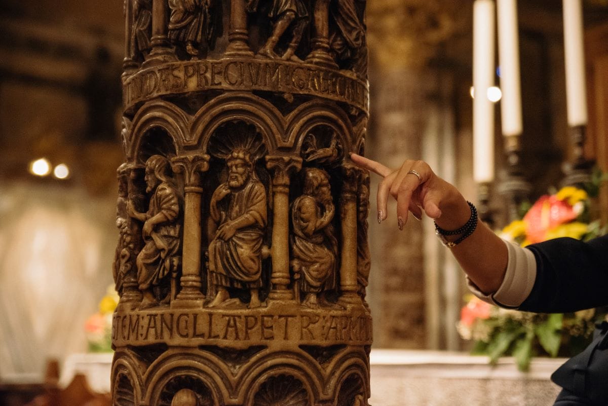 A tour guide pointing out carvings on a column while on a tour of St. Mark’s Basilica.
