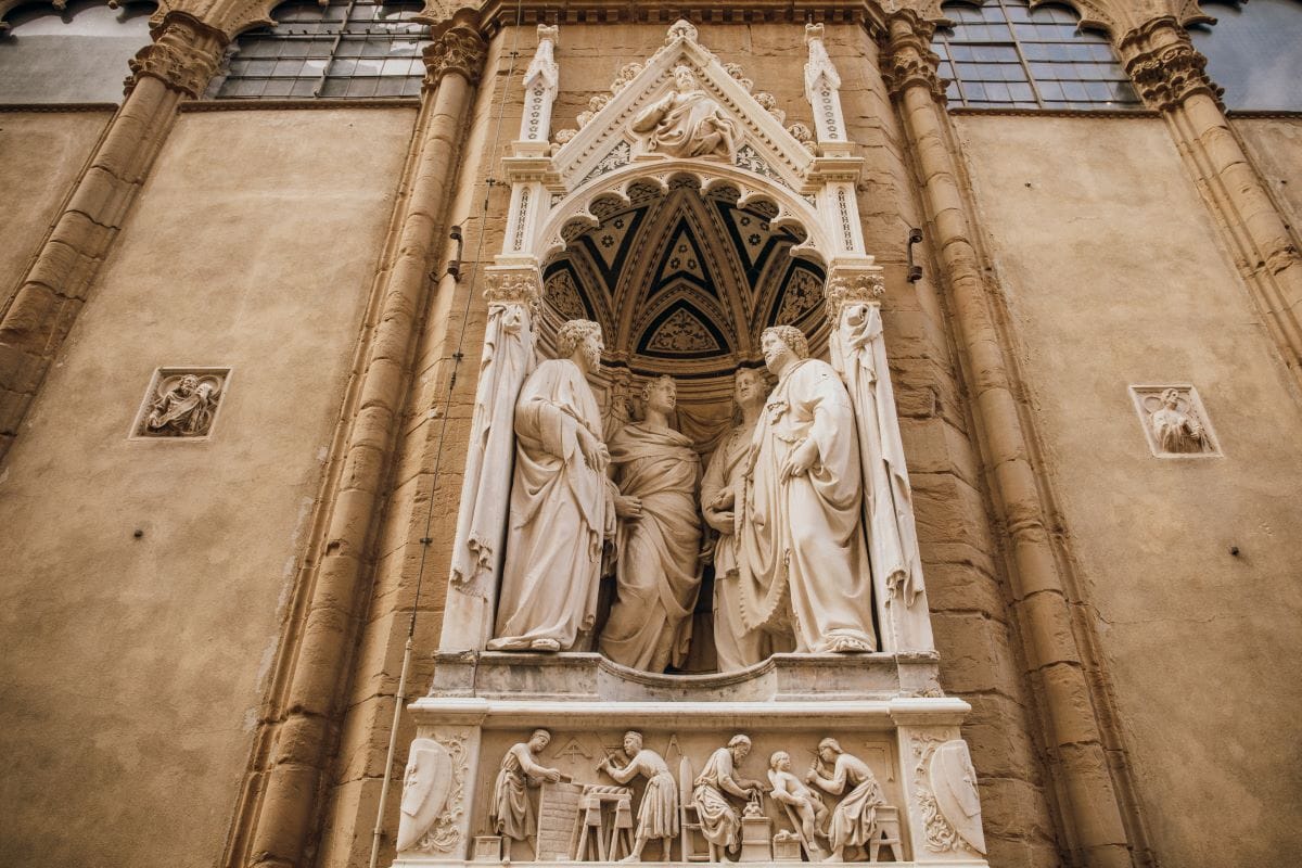 Four statues facing each other in a altar-like space carved into a wall.