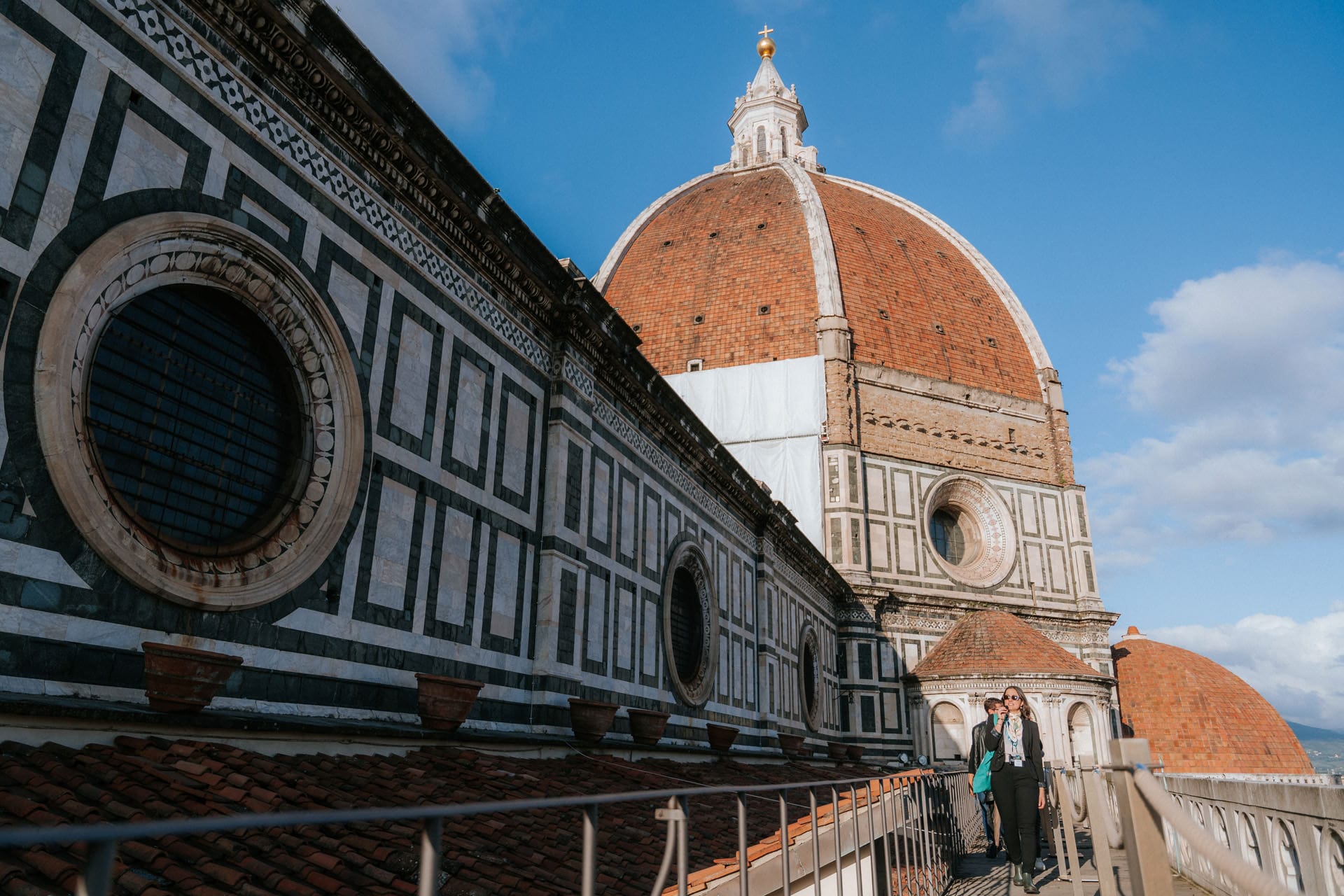 People climbing Florences Duomo with a beautiful view of the iconic cathedral and its intricate marble design.