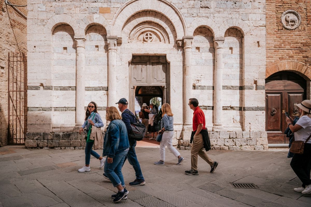 People walking past a church on a tour from Florence to San Gimignano. 