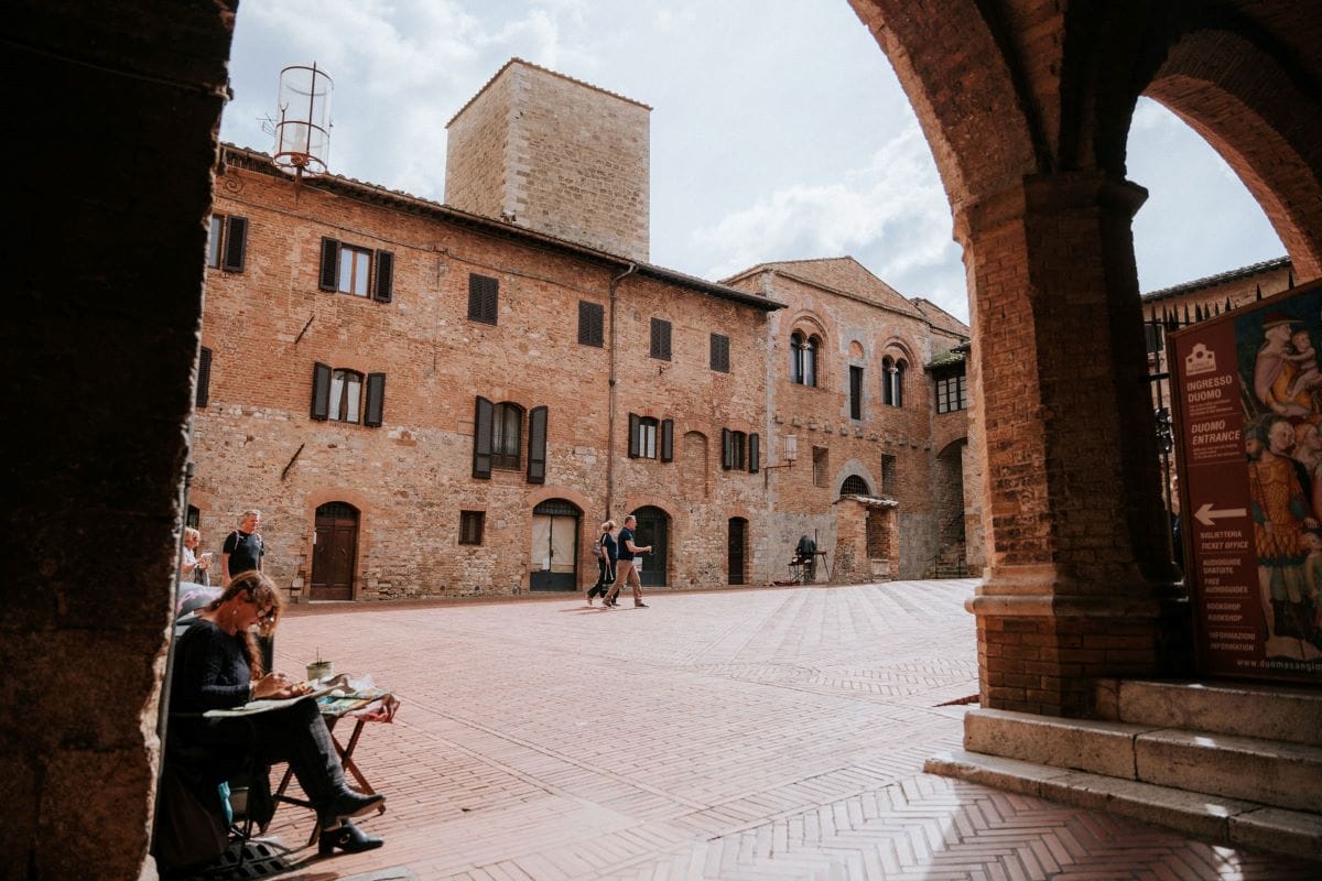 A woman sits in a small square on a day trip from Florence to San Gimignano.