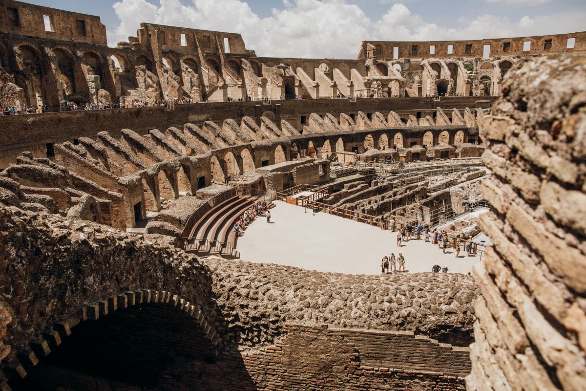 Interior view of the Colosseum with ruins, visible passageways, and an open arena floor.