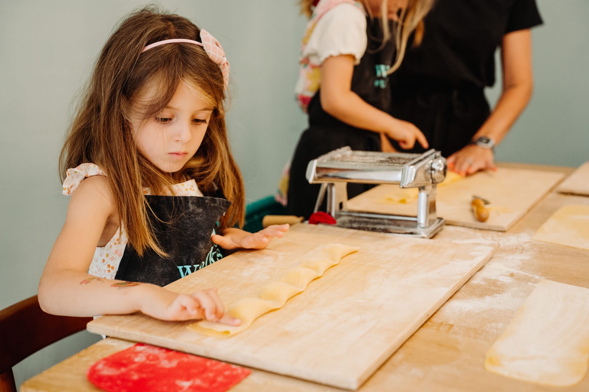 Close-up of a young girl concentrating as she shapes homemade ravioli at her pasta-making station.