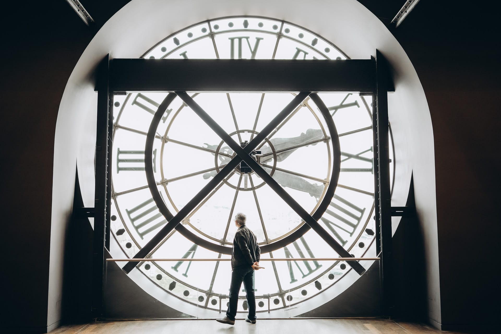 A visitor gazing through the large clock window at the Musée d'Orsay, with an iconic timepiece in view.