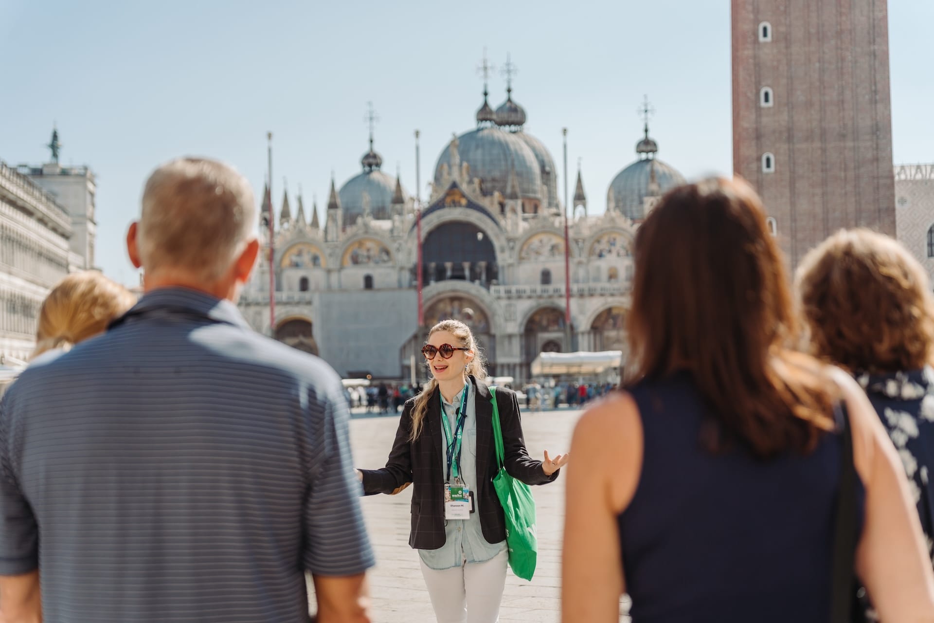 A tour guide speaks to a group of tourists in front of St. Mark's Basilica, on of the top sights to see in venice. 