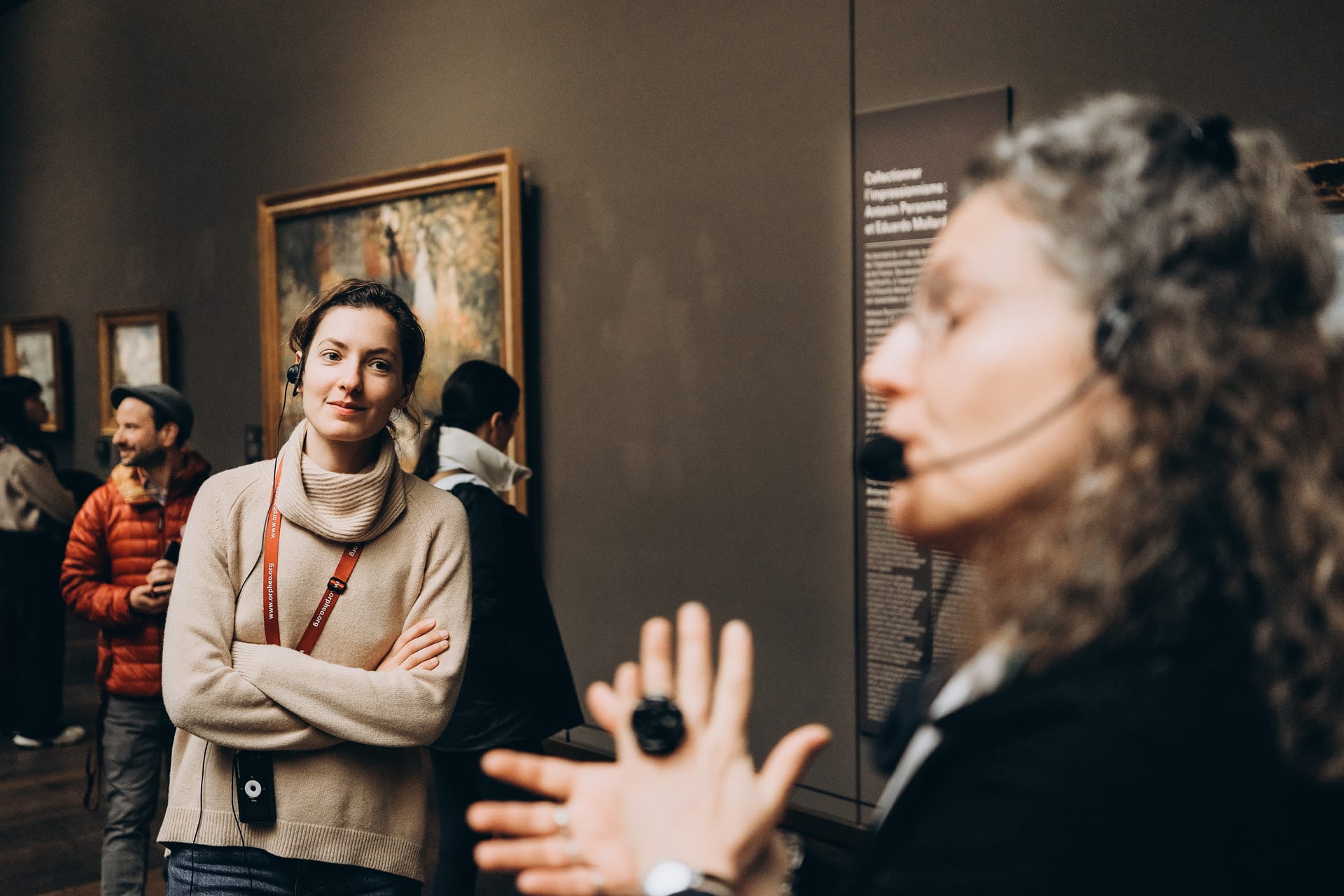 A tour guide explaining artwork to a small group of visitors inside the Musée d'Orsay.