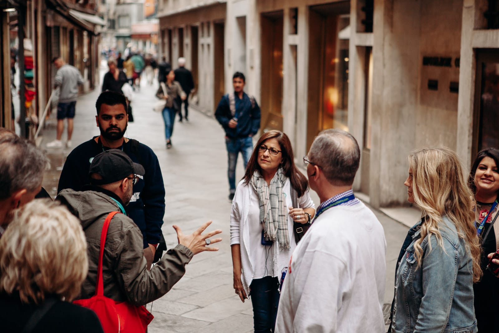 A tour guide telling a story to his group as they walk down a street in Milan