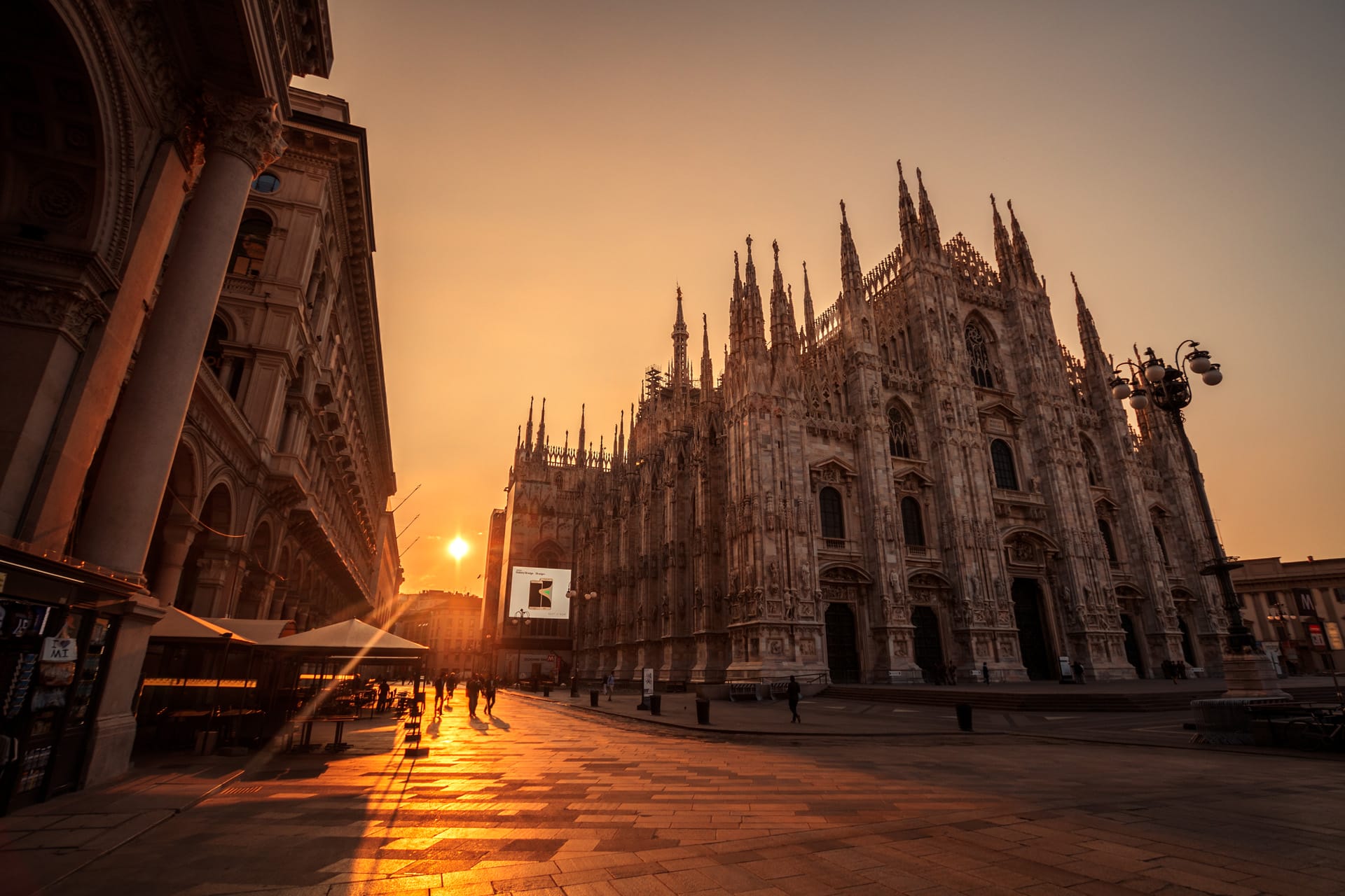 The stunning architecture of the gothic Duomo in Milan, in front of a beautiful orange sunset.