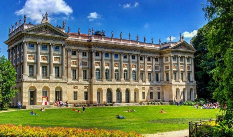 The impressive building of the Villa Reale in Milan, behind a green lawn and gardens. 