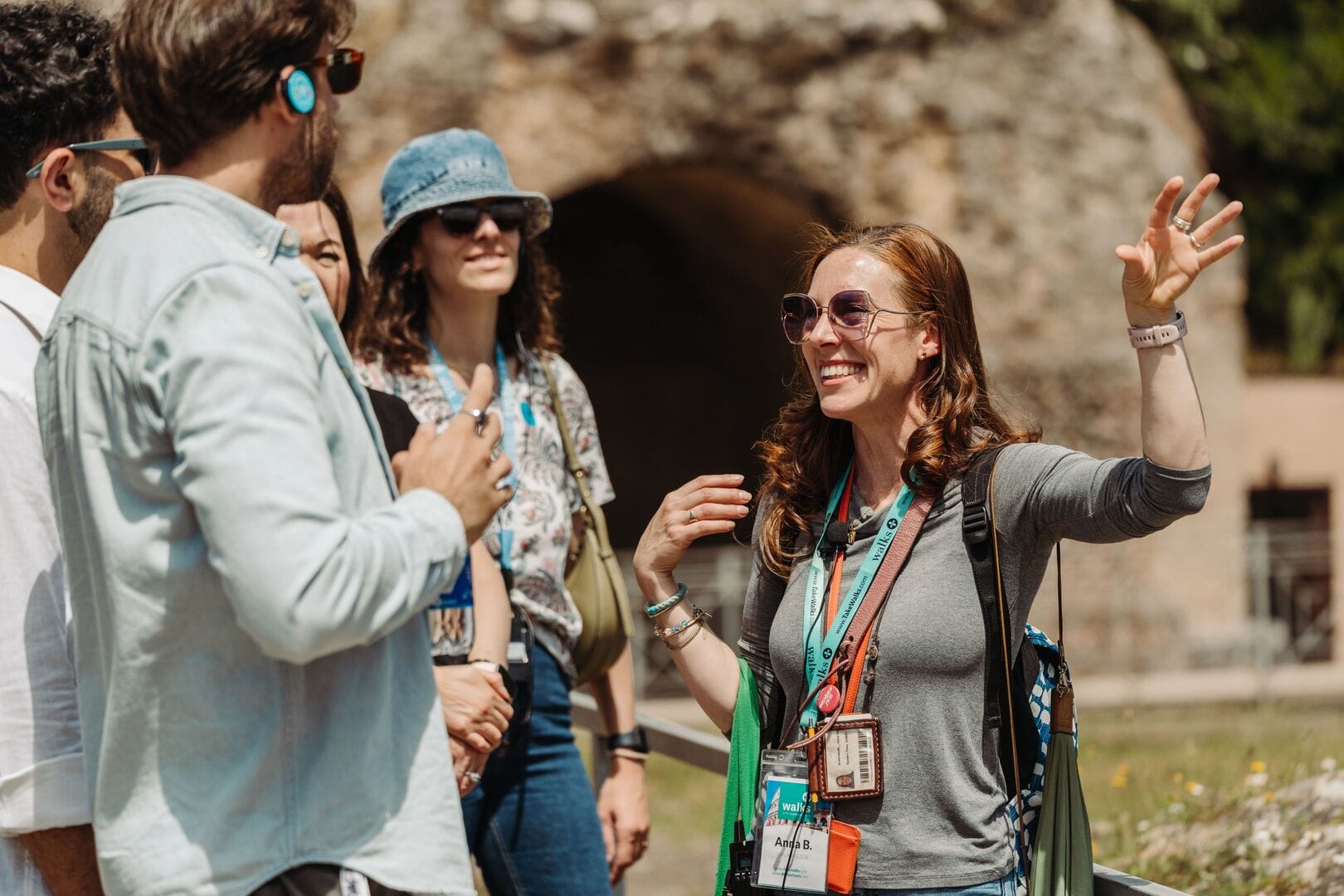 A smiling tour guide speaks to a group of young tourists about Rome, one of the must-visit cities in Italy.