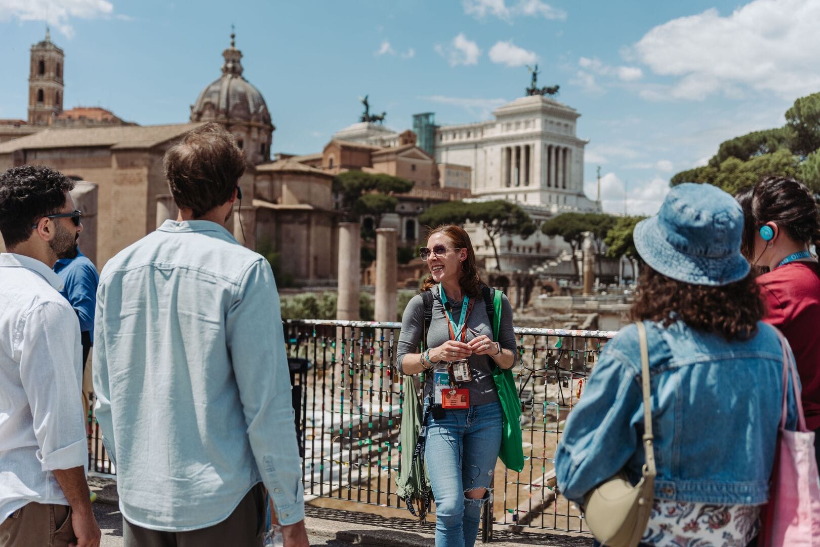 a happy tour guide stands in front of the roman forum with a small tour group
