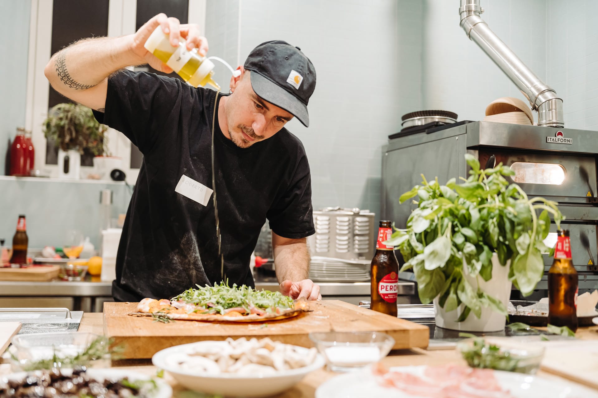 A chef pours olive oil on a homemade pizza, in a cooking in rome