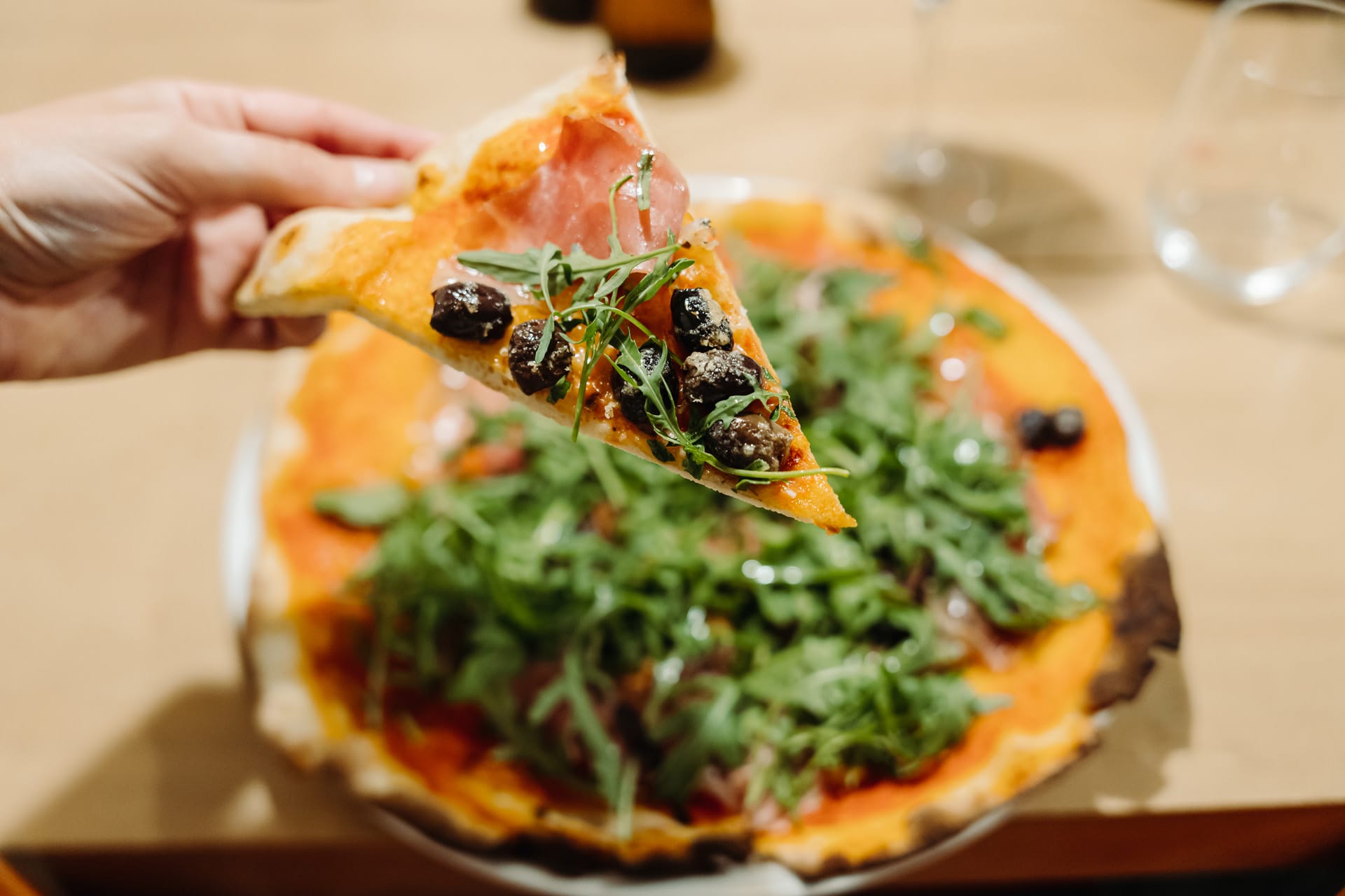 A traditional italian pizza with a slice cut out being put up by a hand