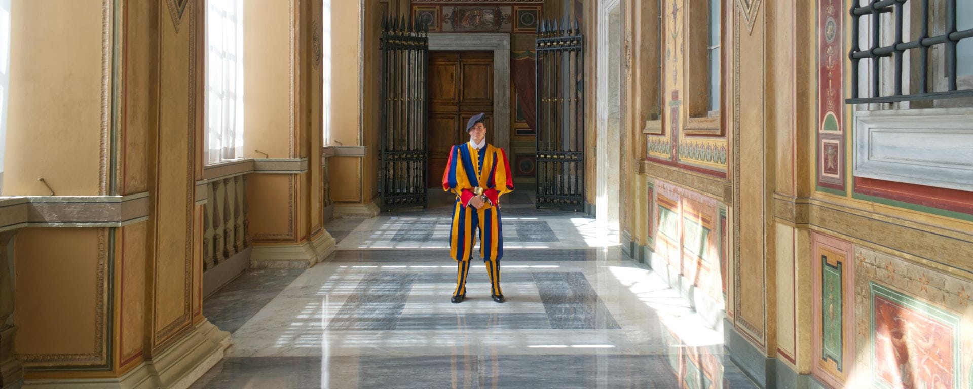 a member of the Swiss guard stand in a corridor of the one of the official buildings he serves and protects 