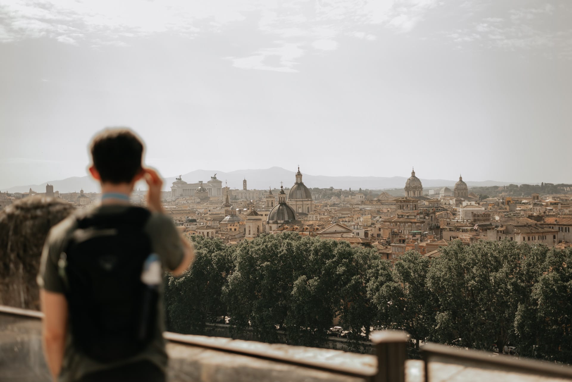 A blurred silhouette of a man looking into the distance: which shows the skyline of Rome, and its many interesting buildings and domes