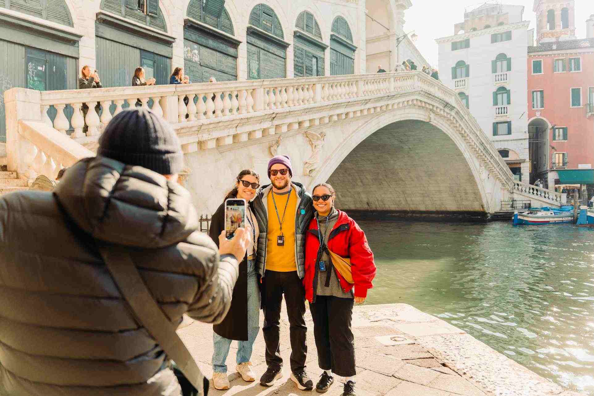 A family taking a photo at the rialto bridge on a rome to venice day trip