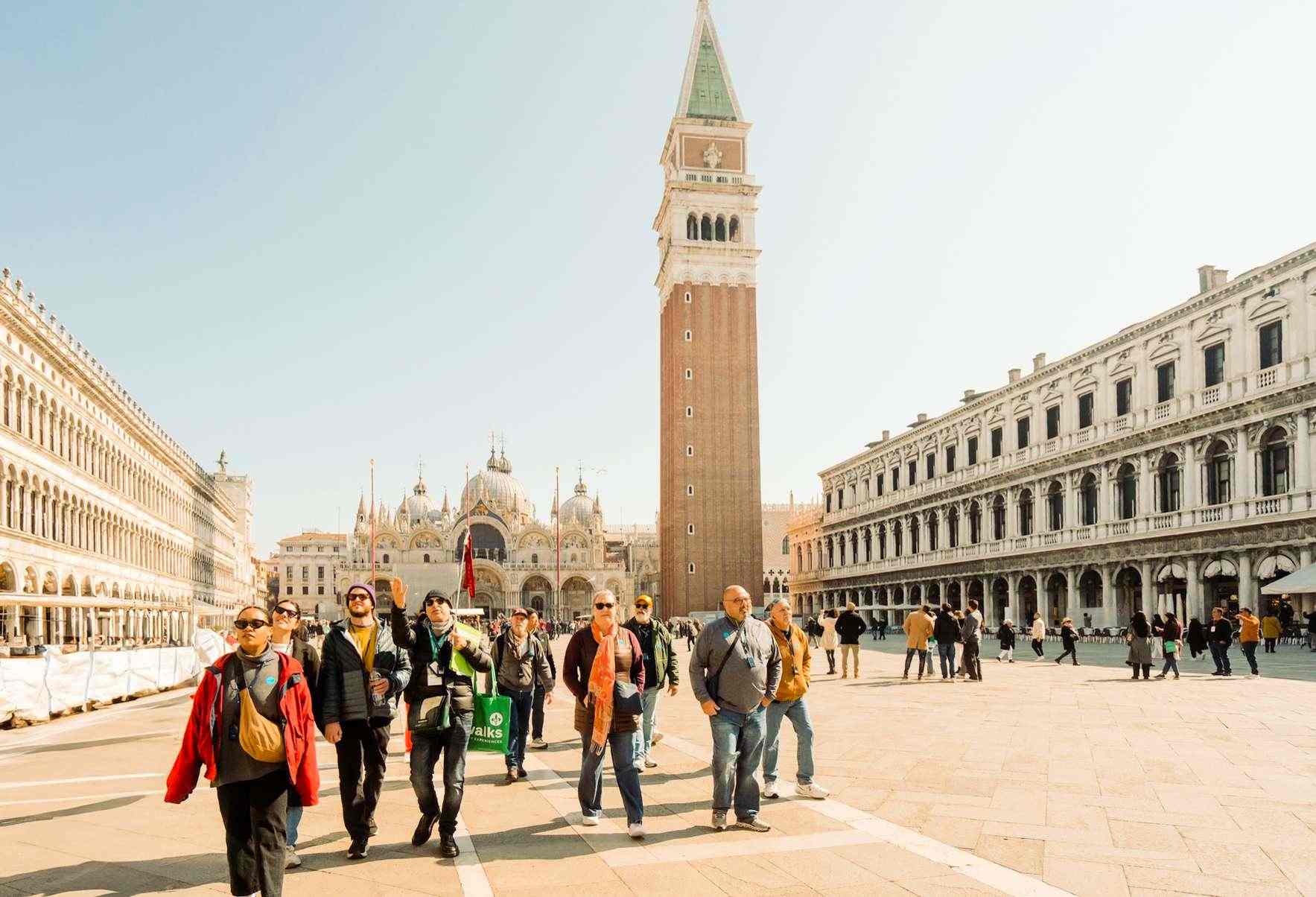 a group of tourists on a rome to venice day trip take in the sights of St Marks Basilica and piazza