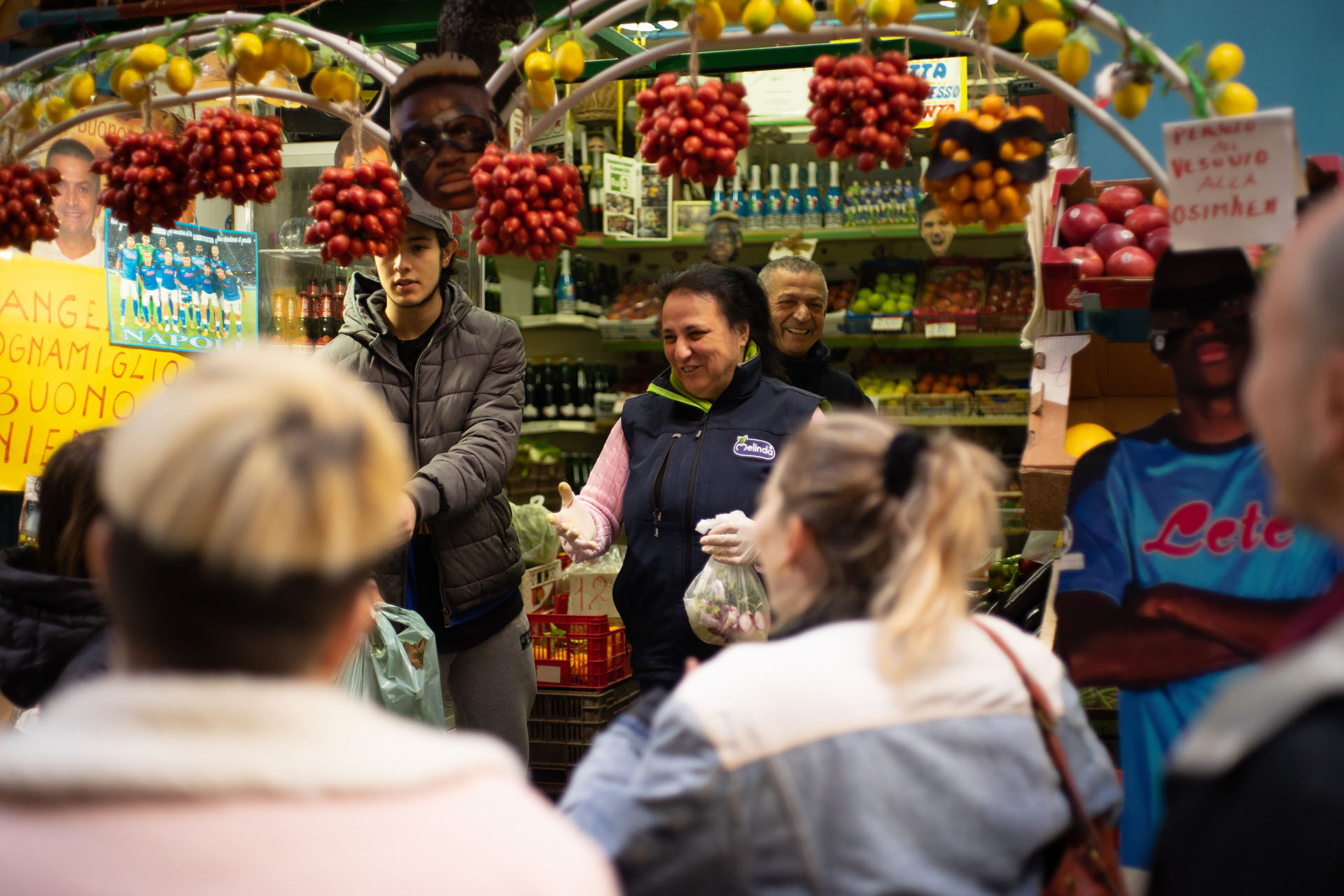 a market stall in Naples, with a vendor surrounded by a crowd of people